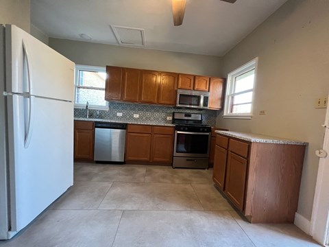 A kitchen with brown cabinets and a white refrigerator.