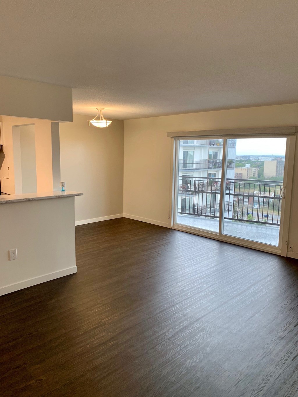 an empty living room with wood flooring and a balcony