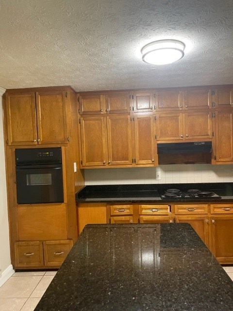 a kitchen with wooden cabinets and a black counter top