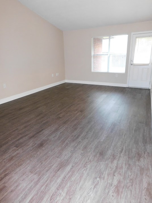 an empty living room with wood floors and a window
