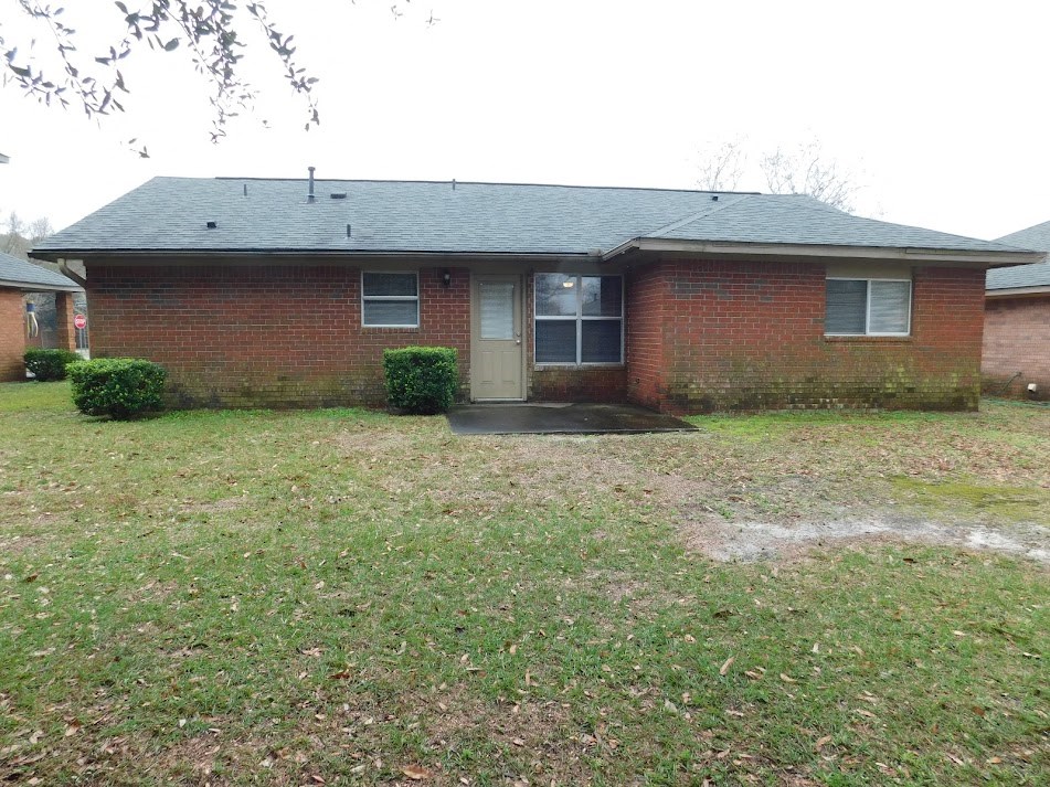 a small brick house with a yard in front of it