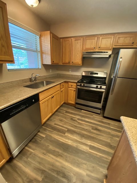 A kitchen with wooden cabinets and a stainless steel refrigerator.