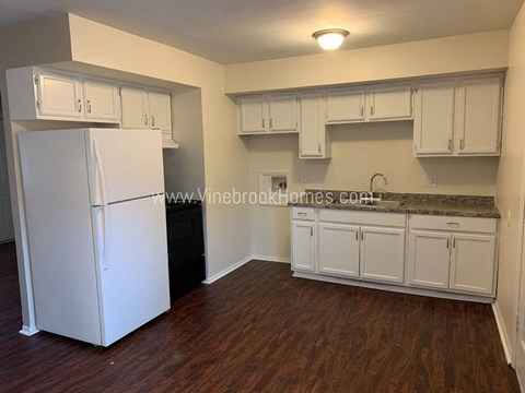 a small kitchen with white cabinets and a refrigerator