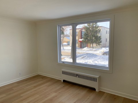 a bedroom with a large window and a wood floor