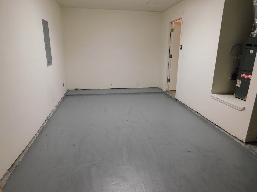 a room with a gray floor and a white wall