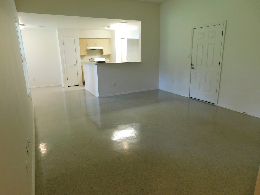 an empty living room and kitchen with a concrete floor