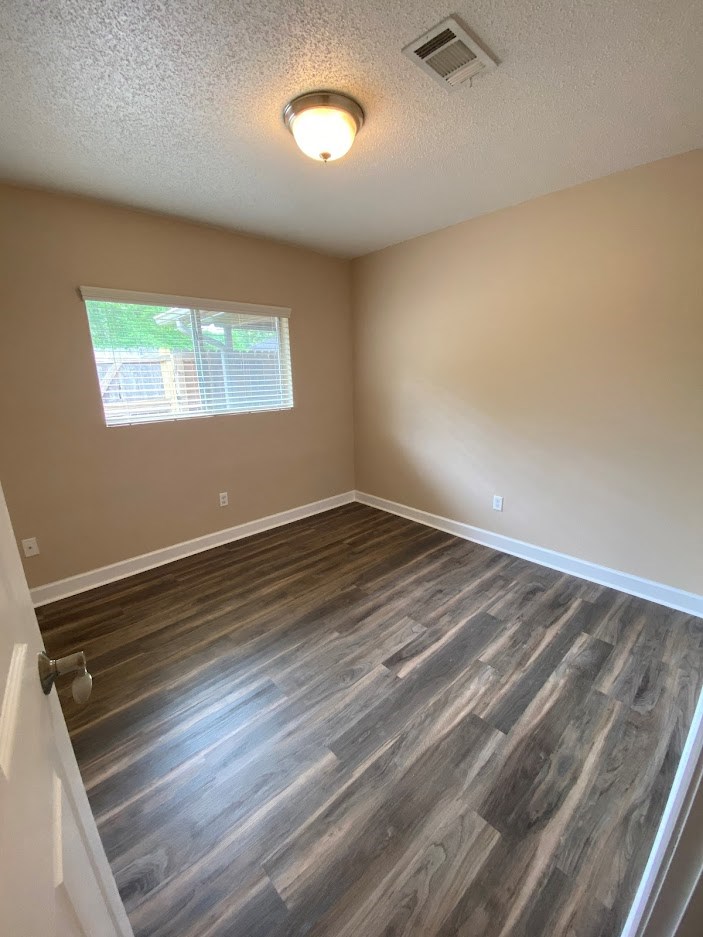 an empty room with wooden floors and a window