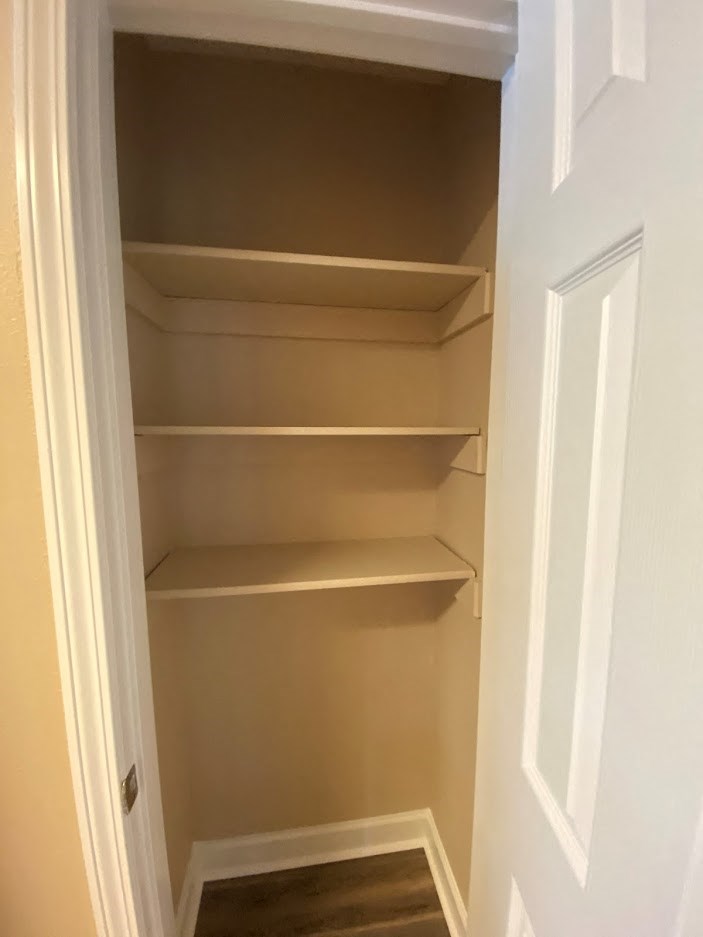 a small closet with three shelves and a door