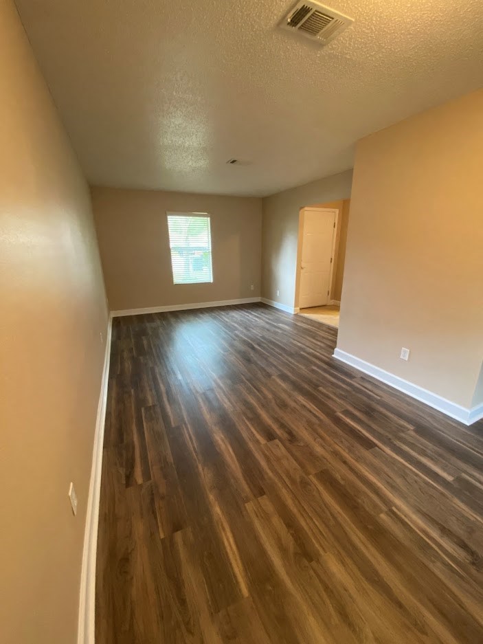 an empty living room with a hard wood floor