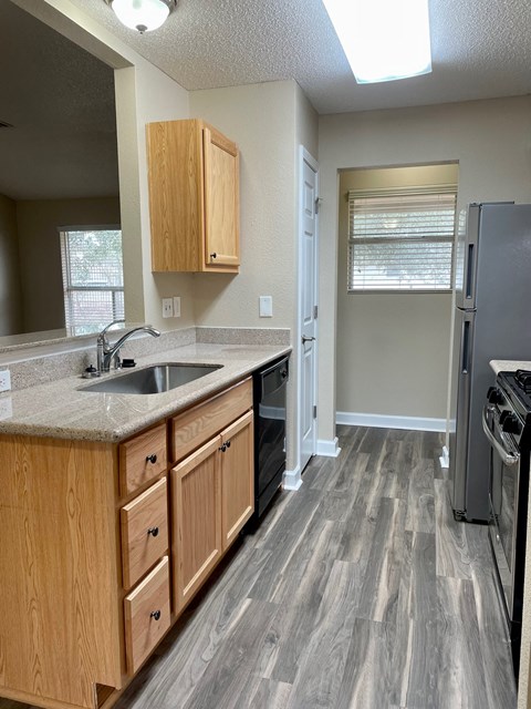 A kitchen with wooden cabinets and a black fridge.
