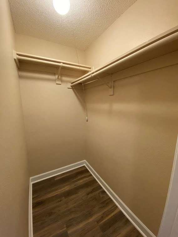 a walk in closet in an empty room with wooden floors