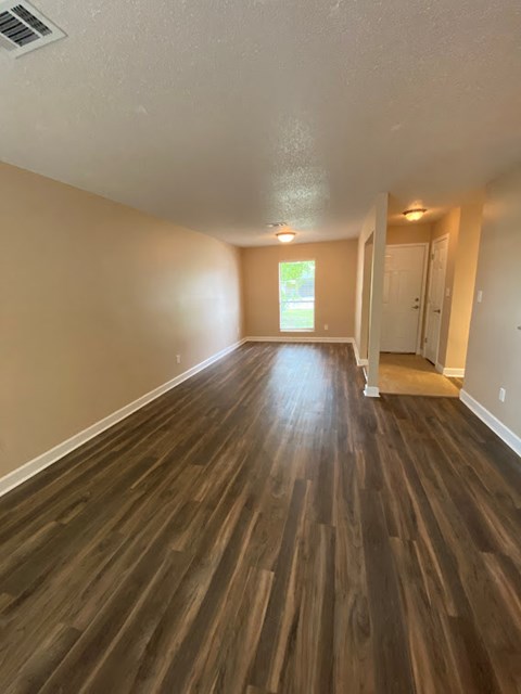 an empty living room with a hard wood floor