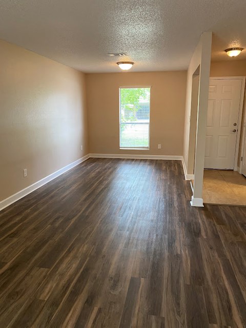an empty living room with a hard wood floor