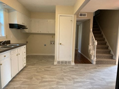 an empty kitchen with a sink and a staircase