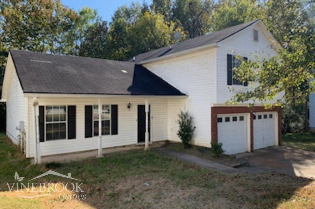 a small white house with a garage and a lawn