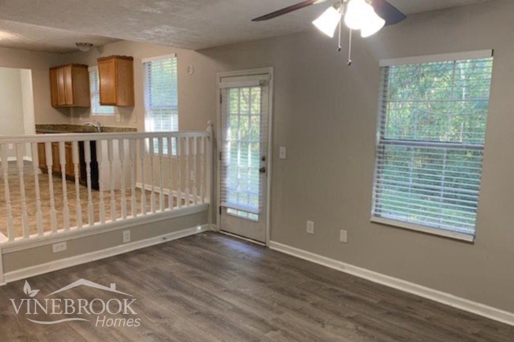 an empty living room with a railing and a door to a kitchen