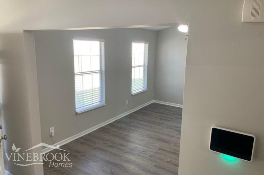 a living room with white walls and wood flooring and a window