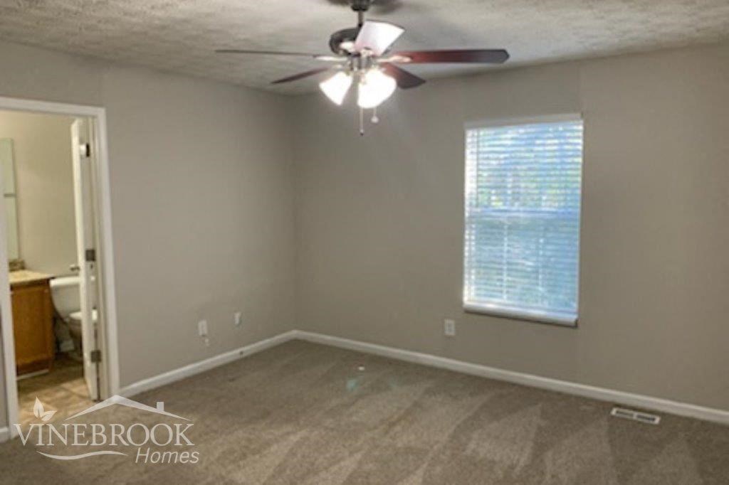 an empty living room with a ceiling fan and a window