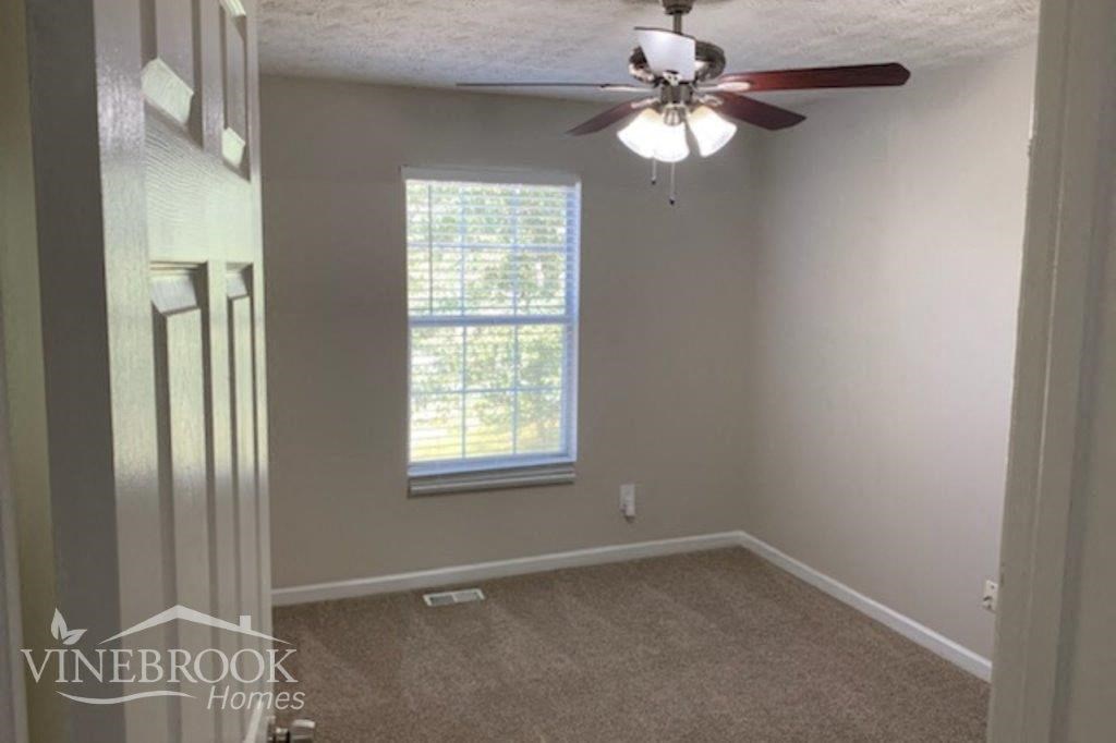 a empty room with a ceiling fan and a window