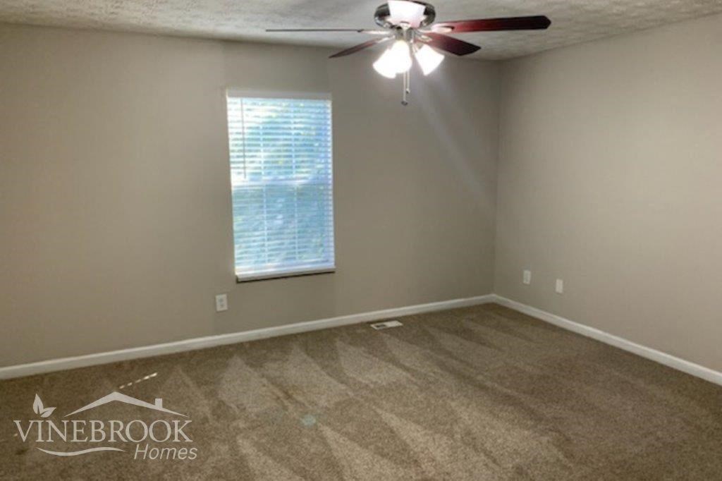 a empty living room with a ceiling fan and a window