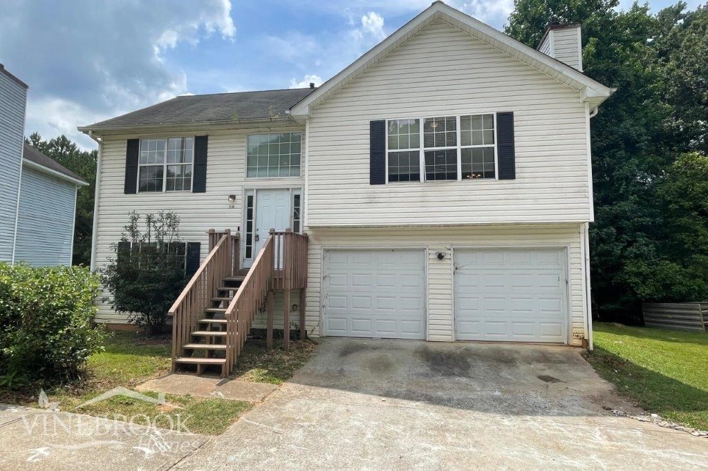 the front of a white house with a driveway and a garage door
