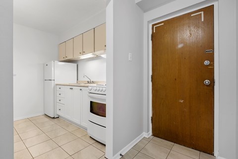 A kitchen with white appliances and a wooden door.