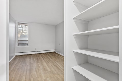 Empty room with white shelves and wooden floor.