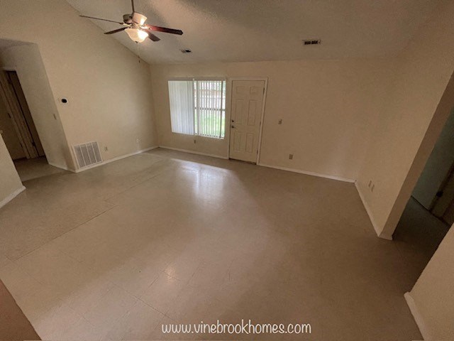 A spacious room with a ceiling fan and a window with blinds.