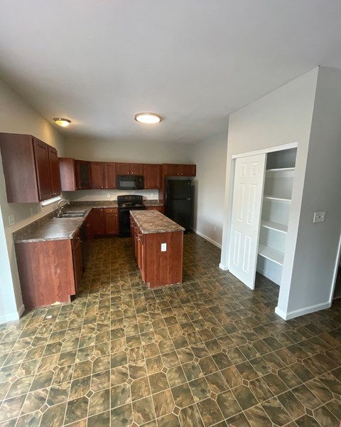 an empty kitchen with wooden cabinets and tile flooring