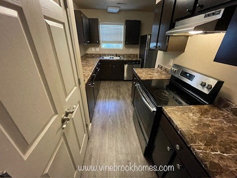A kitchen with a black countertop and a stove top oven.