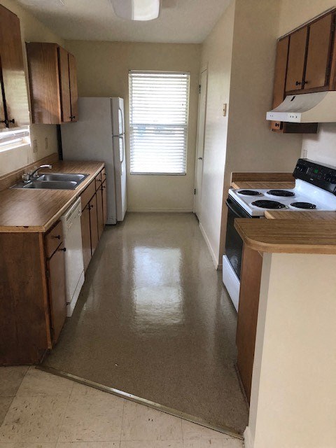 A kitchen with a white fridge and a stove top oven.