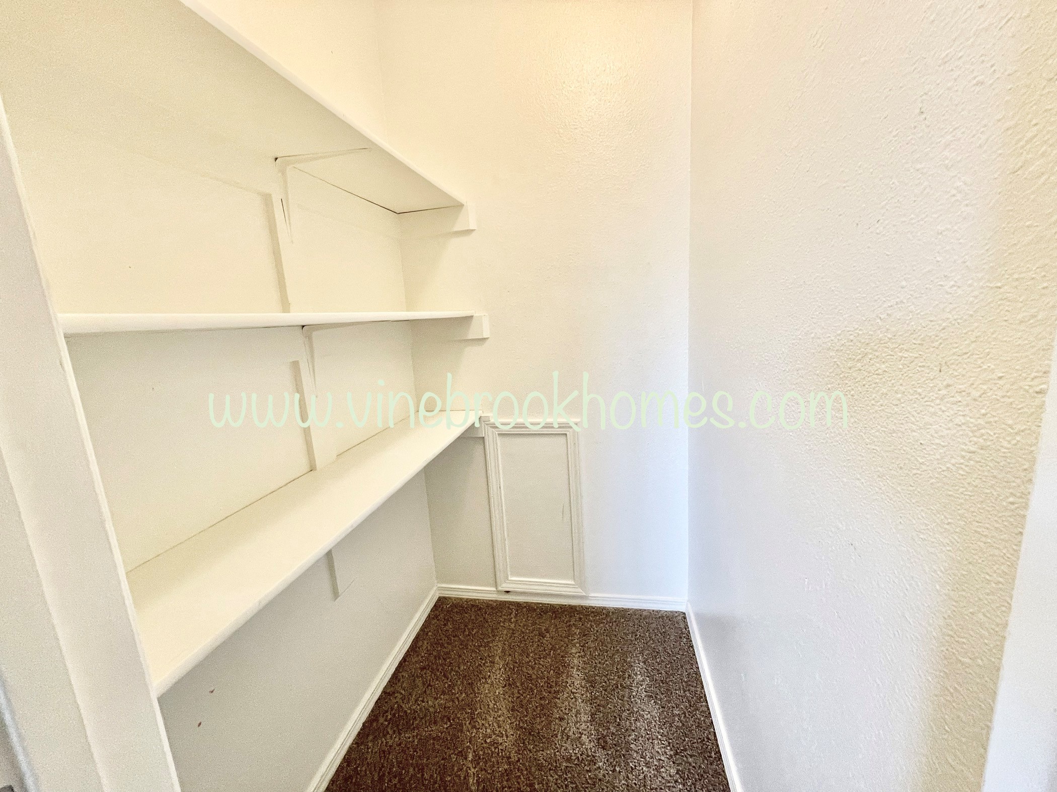 a small closet with white shelves and a white wall
