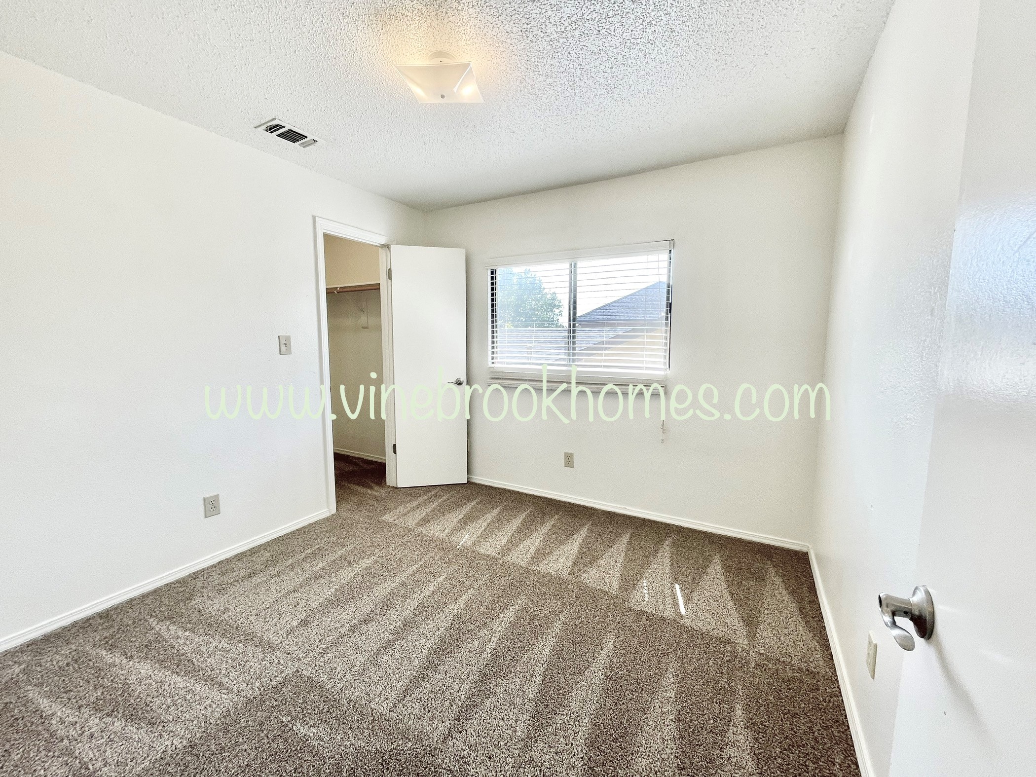 an empty living room with carpet and a door to a closet