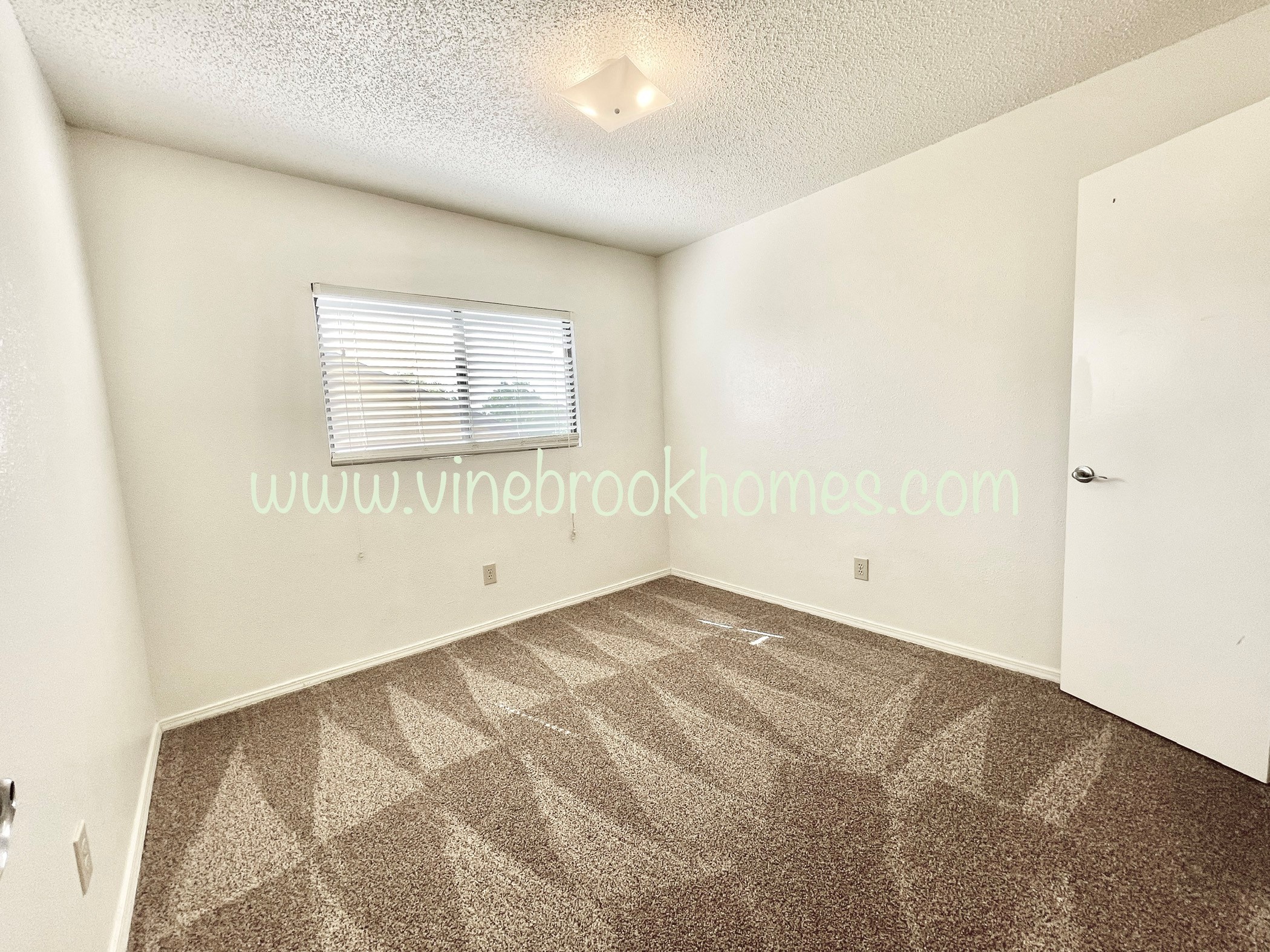 a white bedroom with a carpeted floor and a window