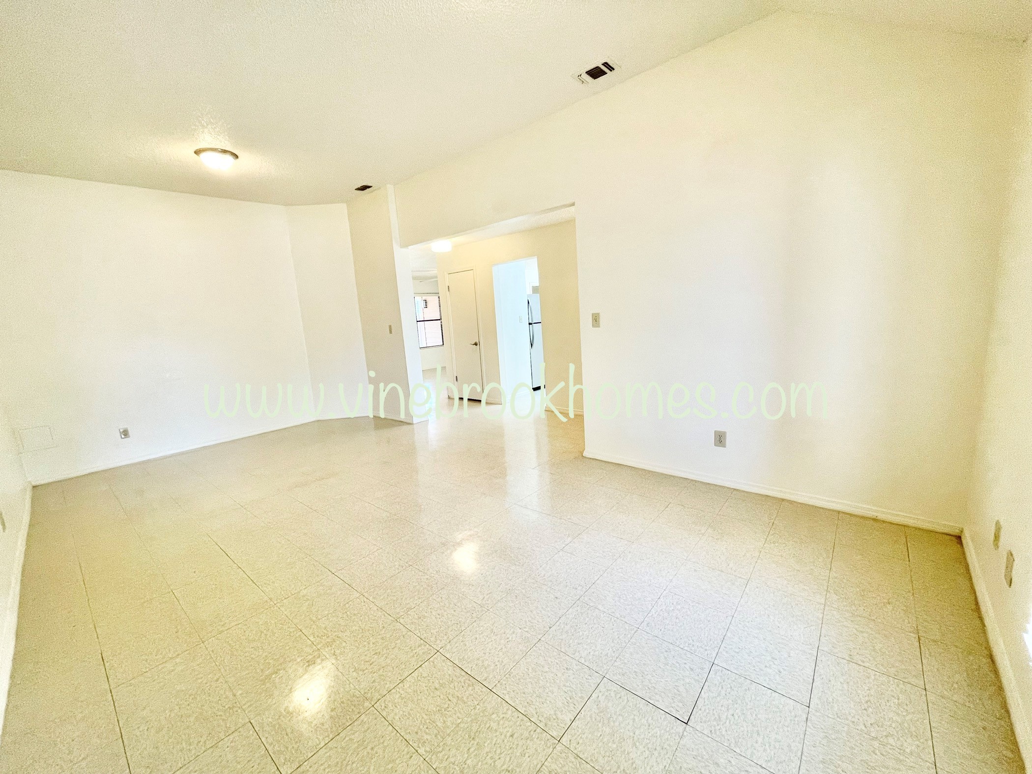 an empty living room with white walls and tiled floor