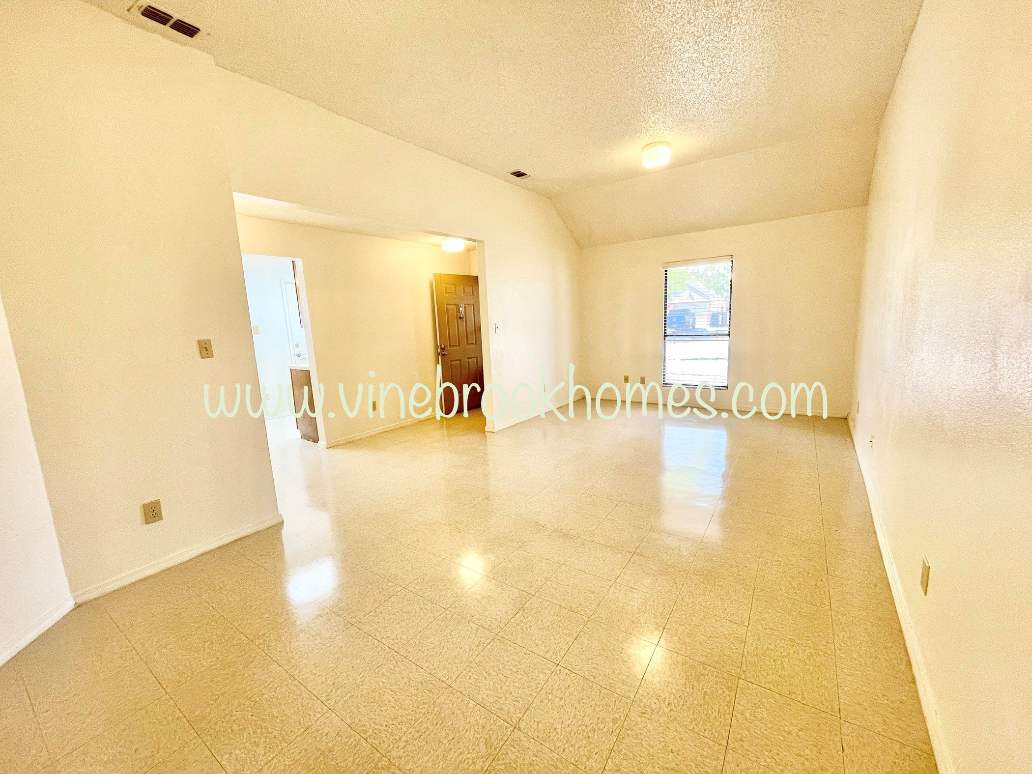 a large living room with a beige tile floor and white walls