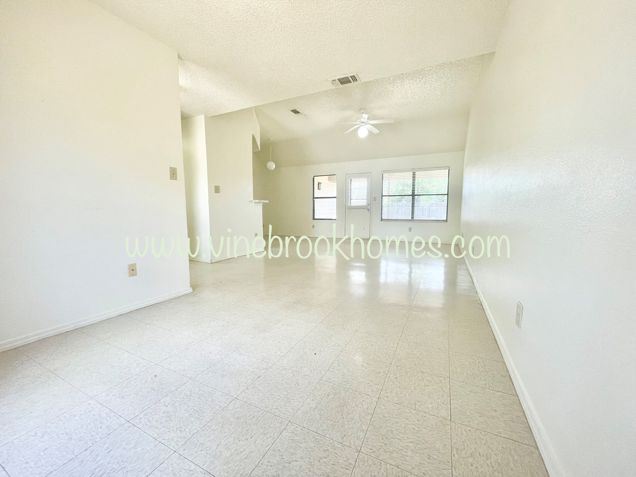 a large living room with white tile floors and white walls