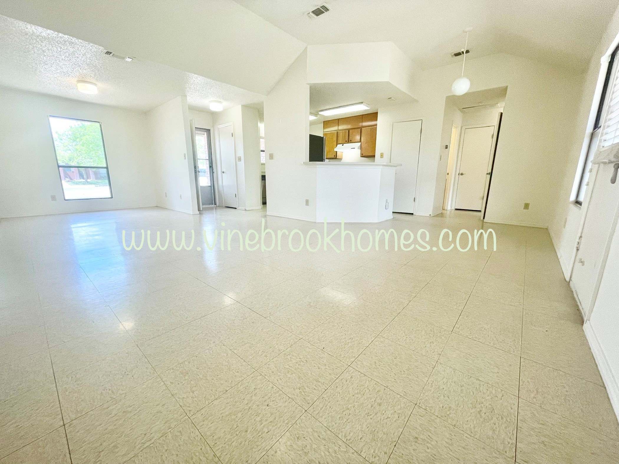 a large living room with a kitchen and a large tiled floor
