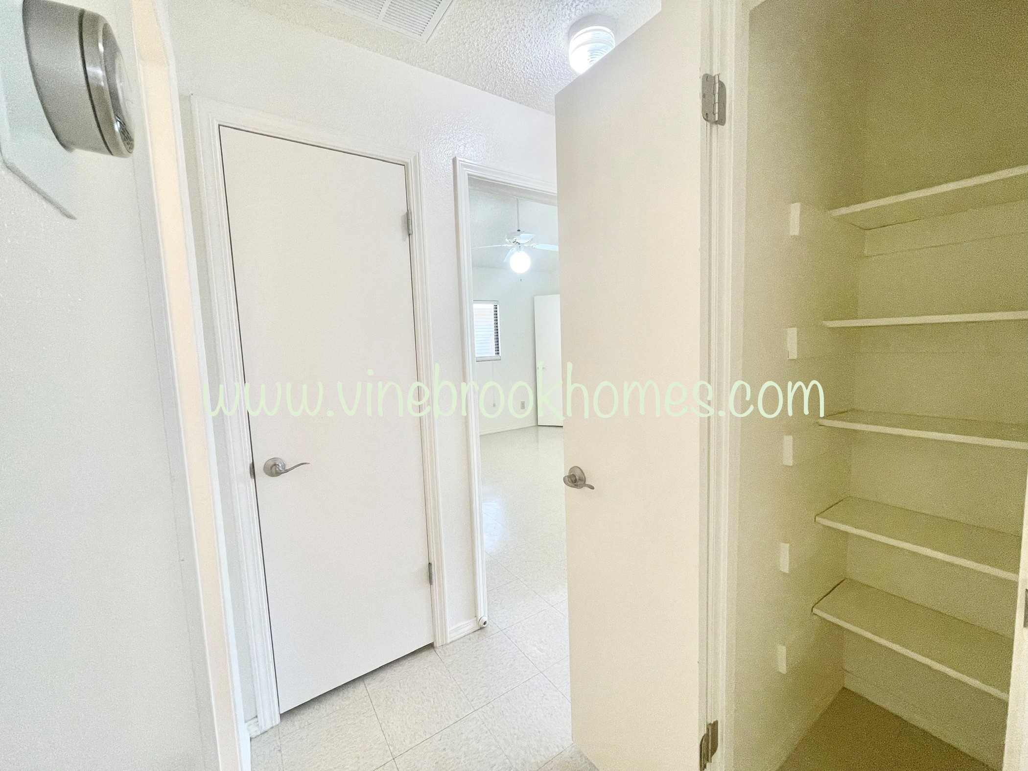 a walk in closet with shelves and a closet door and a white closet