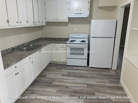 A kitchen with white appliances and cabinets.