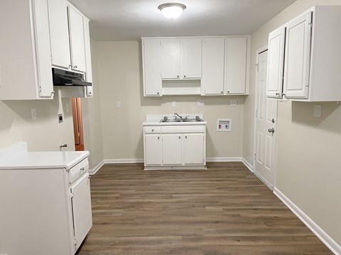 A kitchen with white cabinets and a wooden floor.