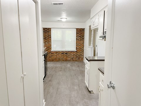 A kitchen with white cabinets and a brick wall.