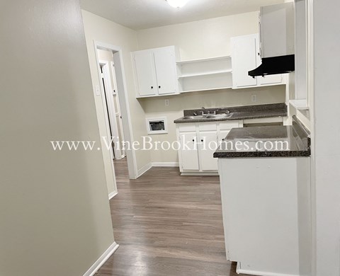 A kitchen with white cabinets and a black range hood.