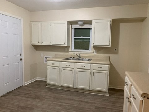 a kitchen with white cabinets and a sink and a window