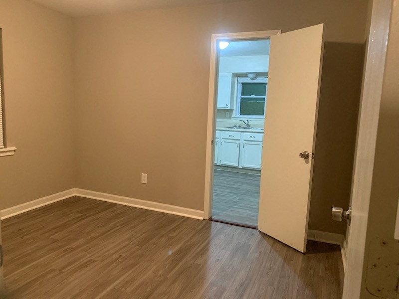 an empty room with a door open to a kitchen