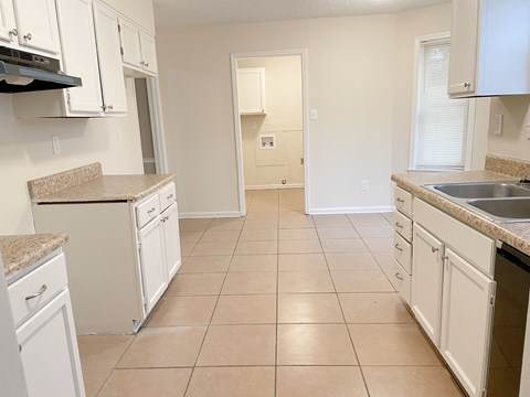 an empty kitchen with white cabinets and tiled flooring