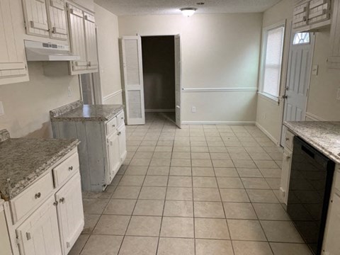 A kitchen with white cabinets and a granite countertop.