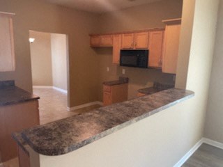 A kitchen with a granite counter top and wooden cabinets.