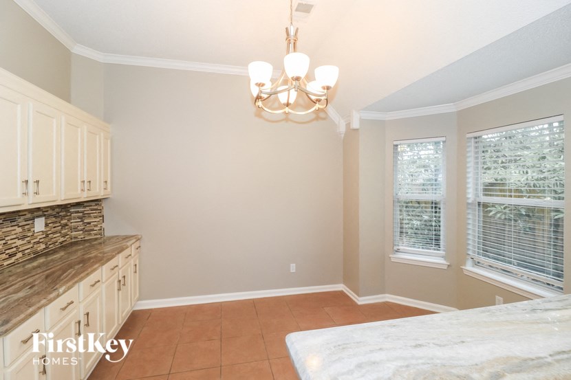 a dining room with a table and a kitchen with a chandelier