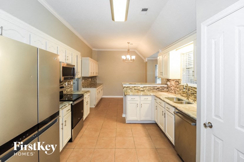 a large kitchen with stainless steel appliances and white cabinets